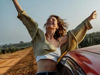 Zeynep leans on the car and smiles.